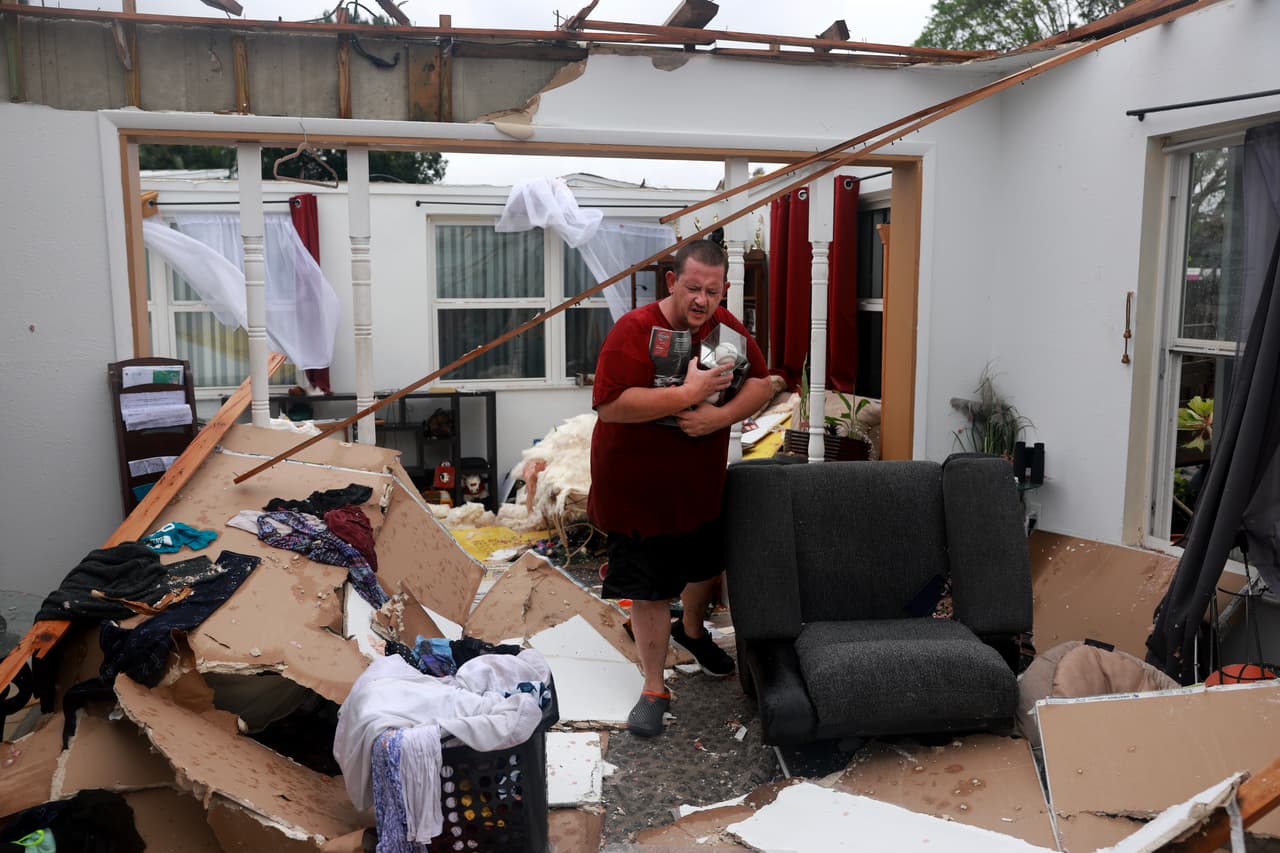 Un hombre camina entre los escombros de una casa en Fort Myers, Florida, que fue afectada por un tornado previo a la llegada del huracán Milton.
