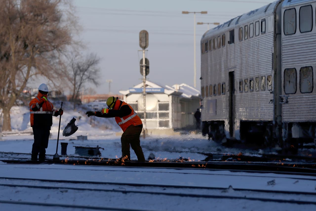 Un tren del servicio Metra se dirige hacia el sur mientras trabajadores dan mantenimiento a vías.
