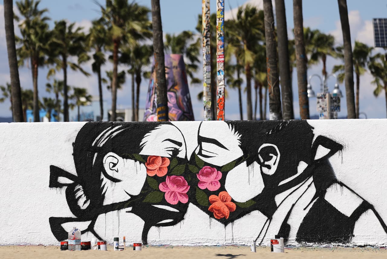 El artista Pony Wave también quiso sumarse a los besos con mascarillas, en este caso coloridas de flores, un grafiti plasmado en un muro de la localidad de Venecia, en California.