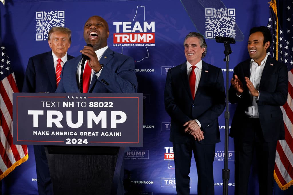 LACONIA, NEW HAMPSHIRE - JANUARY 22: Sen. Tim Scott (R-SC) (2nd-R) speaks as Republican presidential candidate and former President Donald Trump (L), North Dakota Governor Doug Burgum (2nd-R) and Vivek Ramaswamy (R) listen during a campaign rally in the basement ballroom of The Margate Resort on January 22, 2024 in Laconia, New Hampshire. Ramaswamy, Burgum and Scott all ran against Trump for the Republican presidential nomination but later dropped out and endorsed him. Trump is rallying supporters the day before New Hampshire voters will weigh in on the Republican nominating race with the first-in-the-nation primary. (Photo by Chip Somodevilla/Getty Images)