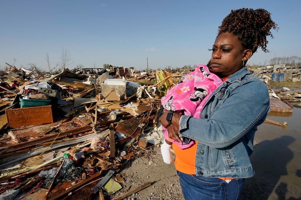 Wonder Bolden carga a su nieta de un año mientras examina los restos de la casa móvil de su madre, arrasada por el tornado en Rolling Folk, Mississippi.