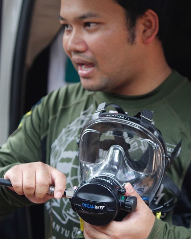 Un trabajador de rescate tailandés muestra una máscara completa a los periodistas en la cueva Tham Luang.