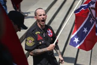 Miembro del Ku Klux Klan con una bandera confederada