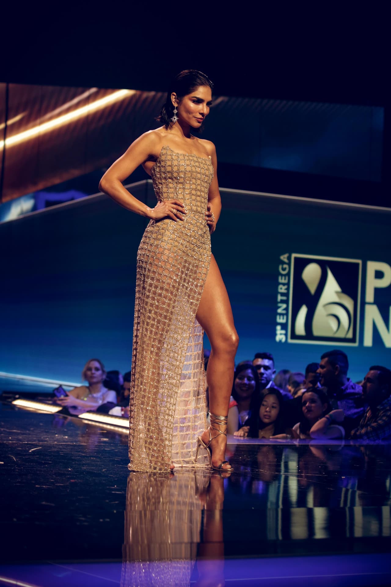 Para entregar otro premio, Alejandra cambió su atuendo por un vestido de corte columna en malla dorada.