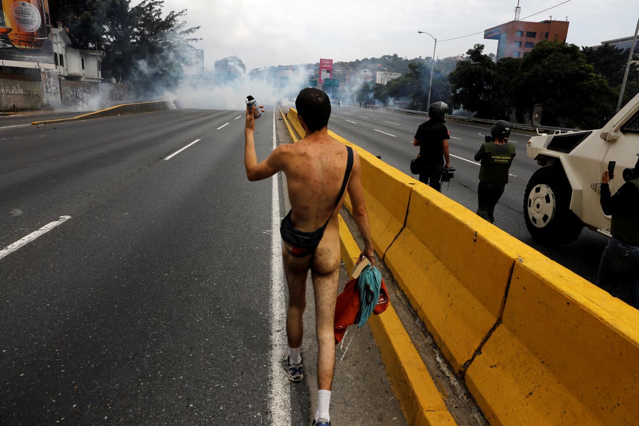 While police threw tear gas he continued walking naked down the street. (Carlos García Rawlins/Reuters)