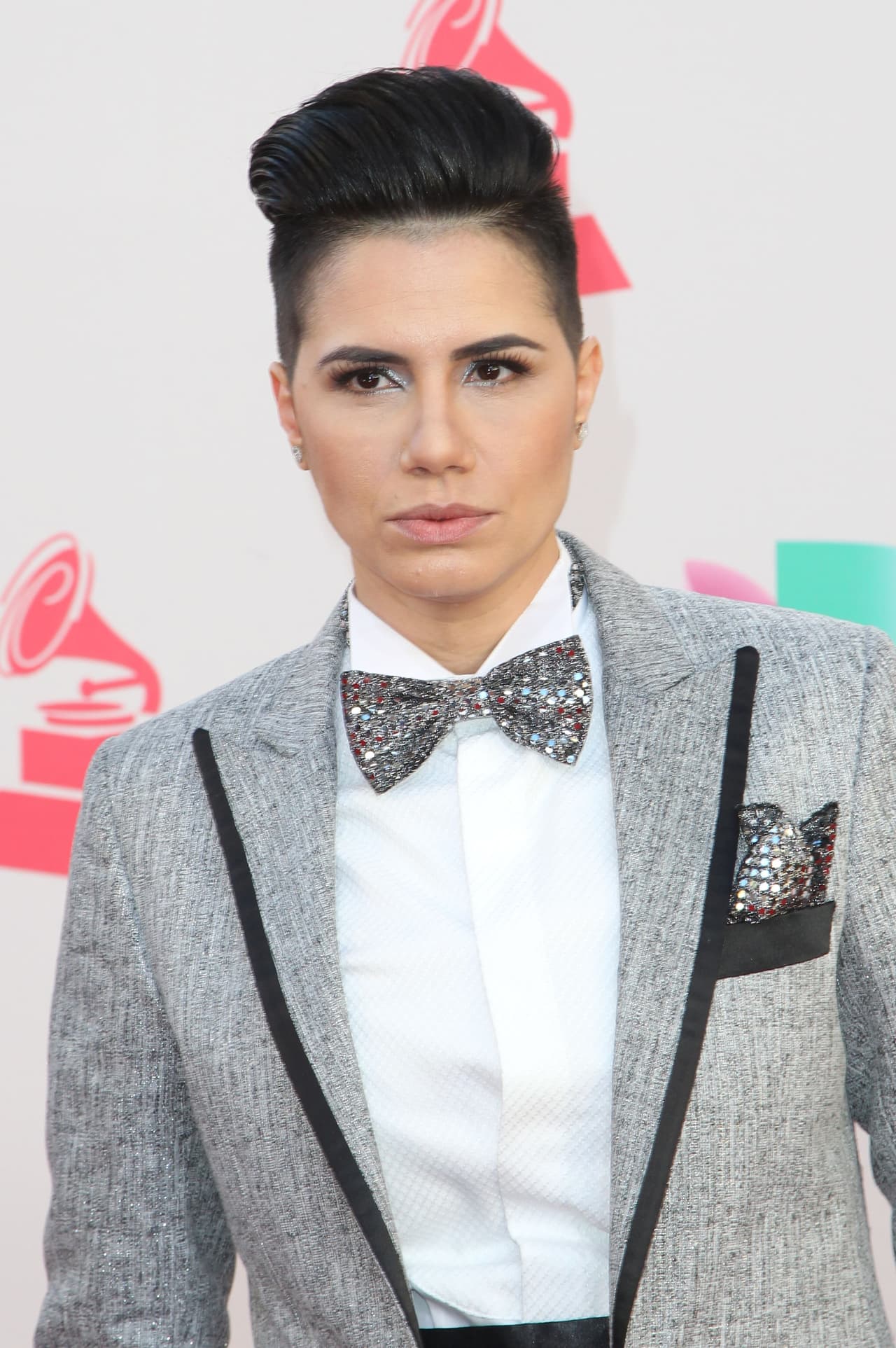 La cantante venezolana Karen Martello con pajarita plateada y pañuelo en la americana a juego.