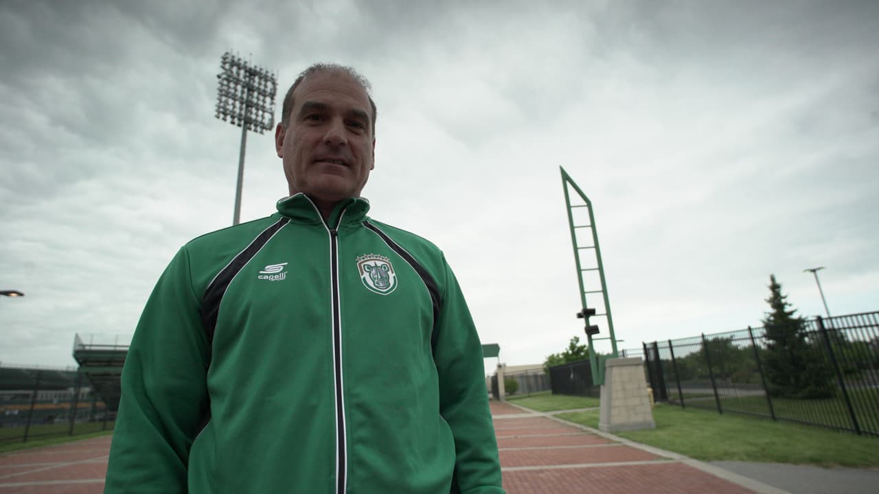 Mark en su ropa de trabajo, la chamarra de los Rochester Rhinos. De fondo, el estadio, donde pasa la mayor parte del día.