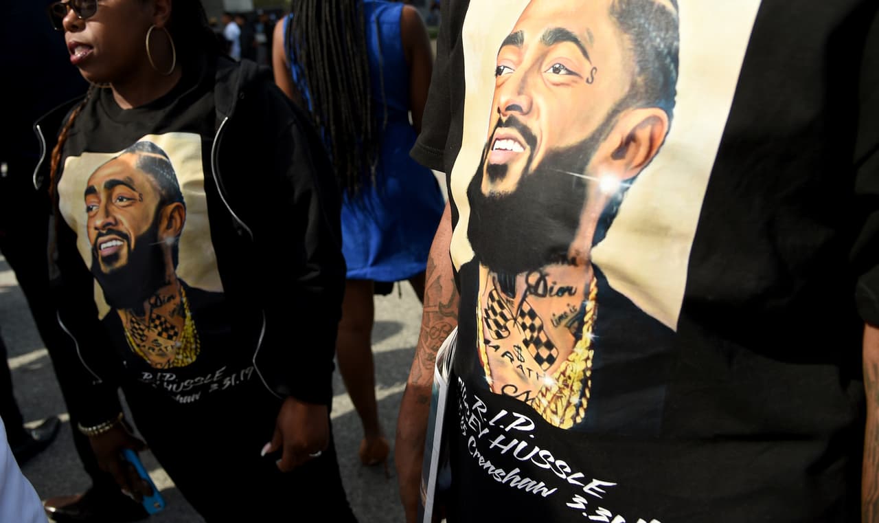 Los asistentes honraron a Nipsey Hussle con su vestimenta. Predominando el estampado de su rostro en camisetas, abrigos, cachuchas y pañelos. (Photo by Chris Pizzello/Invision/AP)
<br>
<br>
<a href="https://www.univision.com/local/los-angeles-kmex/miles-de-fanaticos-dan-el-ultimo-adios-al-rapero-nipsey-hussle">Encuentra toda la información del recorrido del último adiós a Nipsey Hussle aquí. </a>