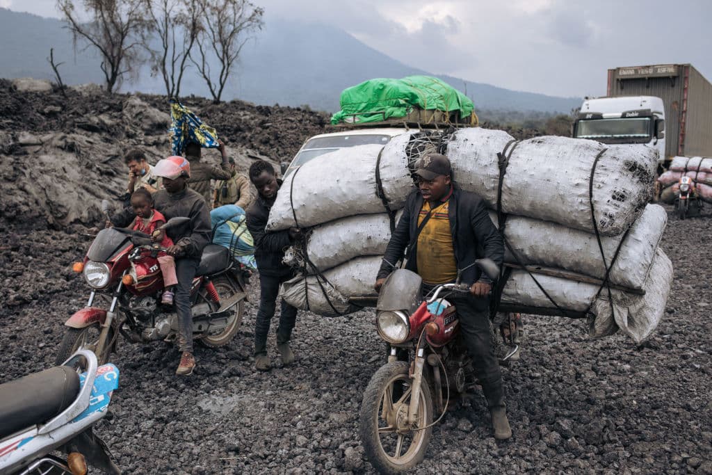 Los transportistas de mercancías conducen sus motocicletas
<b>a través del flujo de lava solidificada del volcán Nyiragongo</b> en los vecindarios del norte de Goma, la capital provincial de Kivu del Norte el 28 de mayo.