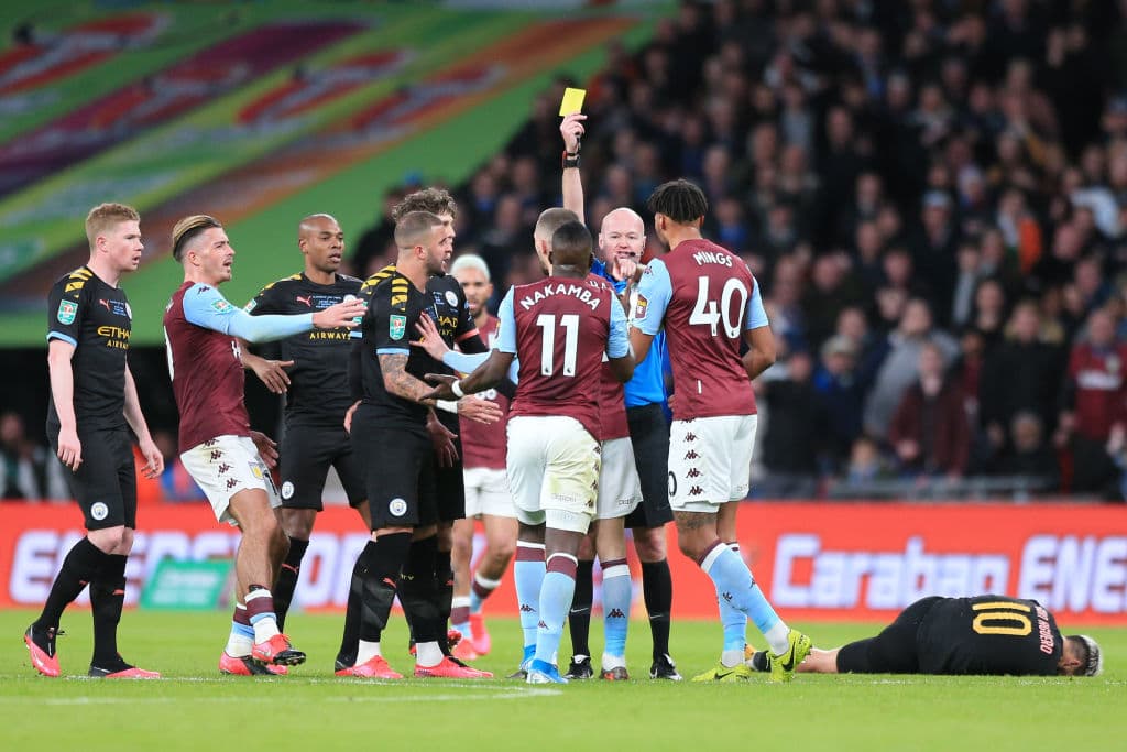 El árbitro, Lee Mason, le muestra la tarjeta amarilla a Nakamba, merecida por la durísima entrada; Mings trata de calmar los ánimos.
