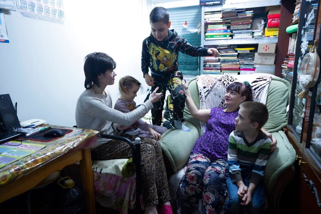 Iryna Bilinskaya, de la región de Luhansk, segunda a la derecha, sentada con sus nietos en el centro de desplazados internos de Kharkiv, busca llevar una vidanormal a pesar de la fuerte tensión que se siente en la región.