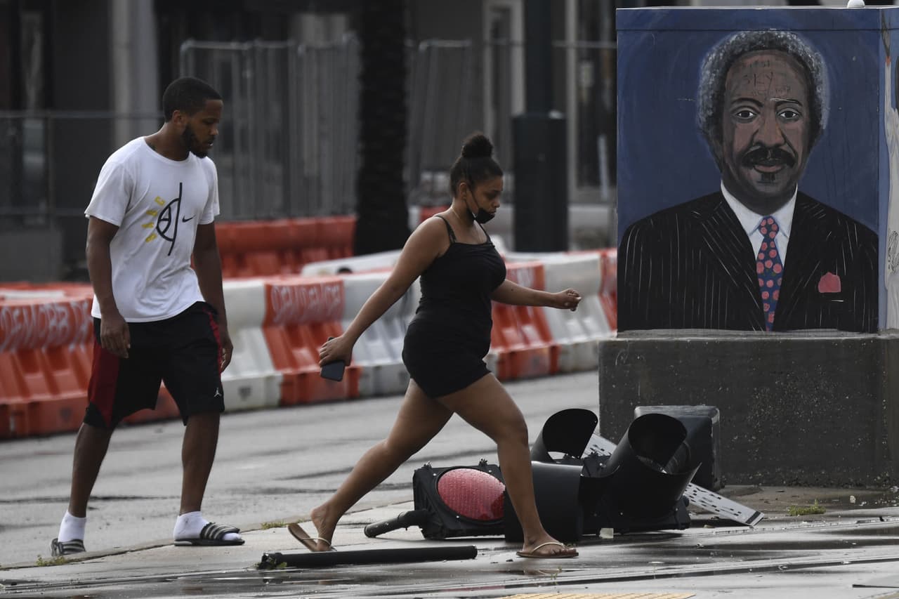 El Centro Nacional de Huracanes advierte que las tormentas y las inundaciones repentinas siguen siendo de alto riesgo en partes de Louisiana, Mississippi y Alabama. En la fotografía, peatones cerca de una señal de tráfico derribada por Ida en Canal Street.