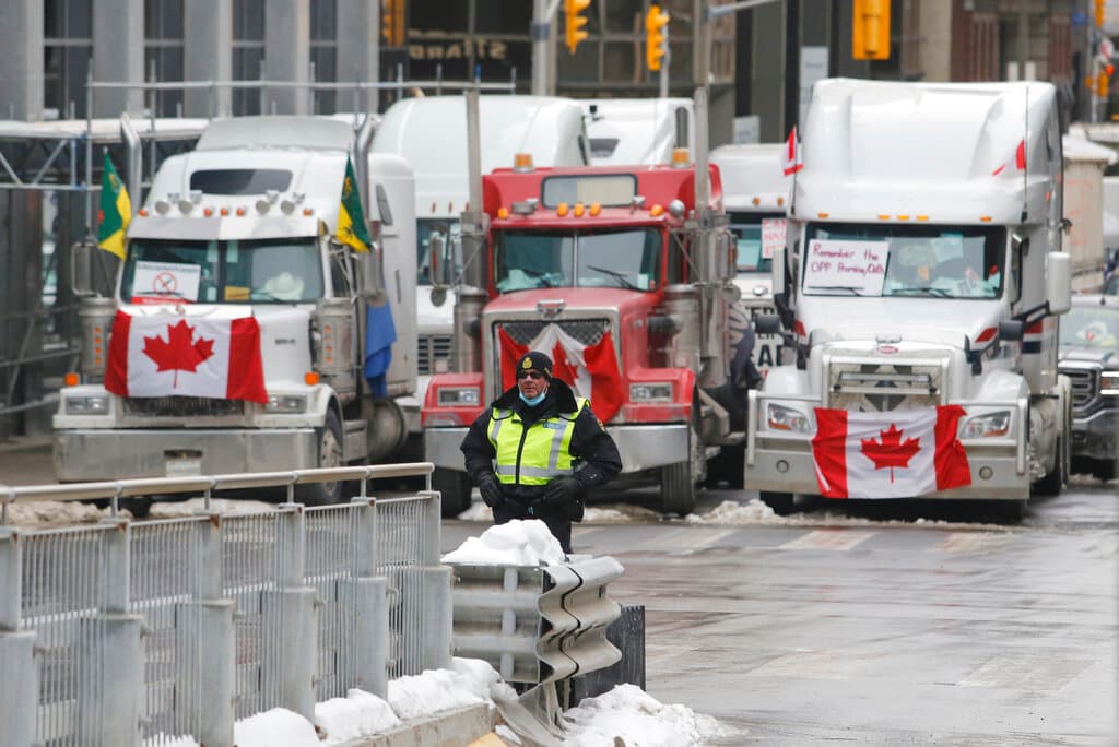 Un policía de pie frente a camiones que bloquean el paso en la frontera con EEUU, el miércoles 9 de febrero de 2022, en Ottawa.