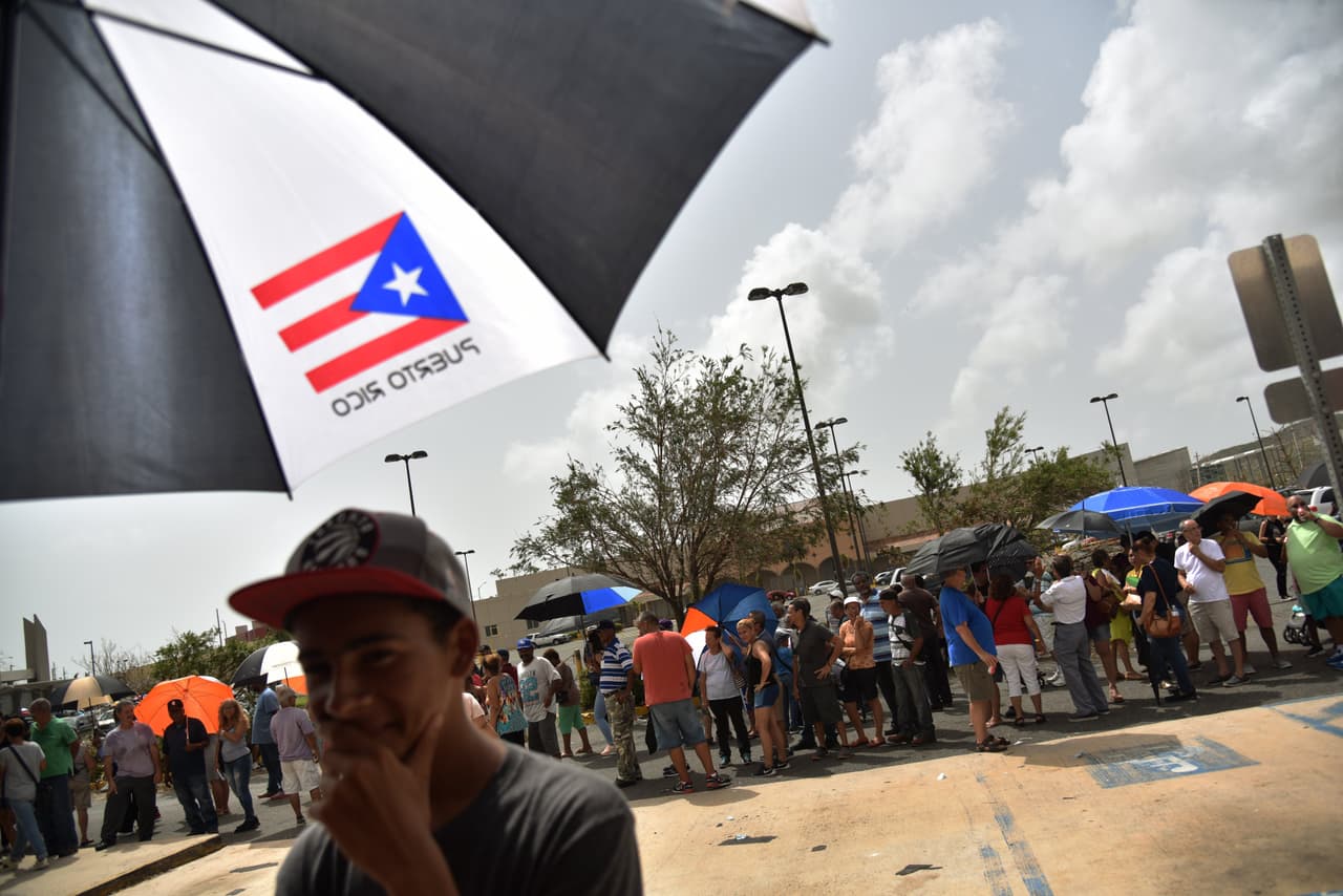People wait in lines to take mony from an ATM in Humacao, in the east of Puerto Rico, on September 27, 2017. The US island territory, working without electricity, is struggling to dig out and clean up from its disastrous brush with the hurricane, blamed for at least 33 deaths across the Caribbean. / AFP PHOTO / HECTOR RETAMAL (Photo credit should read HECTOR RETAMAL/AFP/Getty Images)