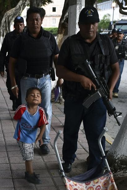 Habitantes de Iguala caminan junto a uno de los cientos de policías desplegados en Iguala.