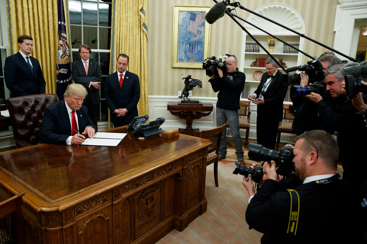 <b>La escultura del vaquero.</b> Donald Trump firma sus primeras órdenes ejecutivas sobre el 
<i>Resolute Desk</i>, el 20 de enero de 2017. A su izquierda el ‘Bronco Buster’, en el mismo lugar donde lo tuvo Barack Obama.