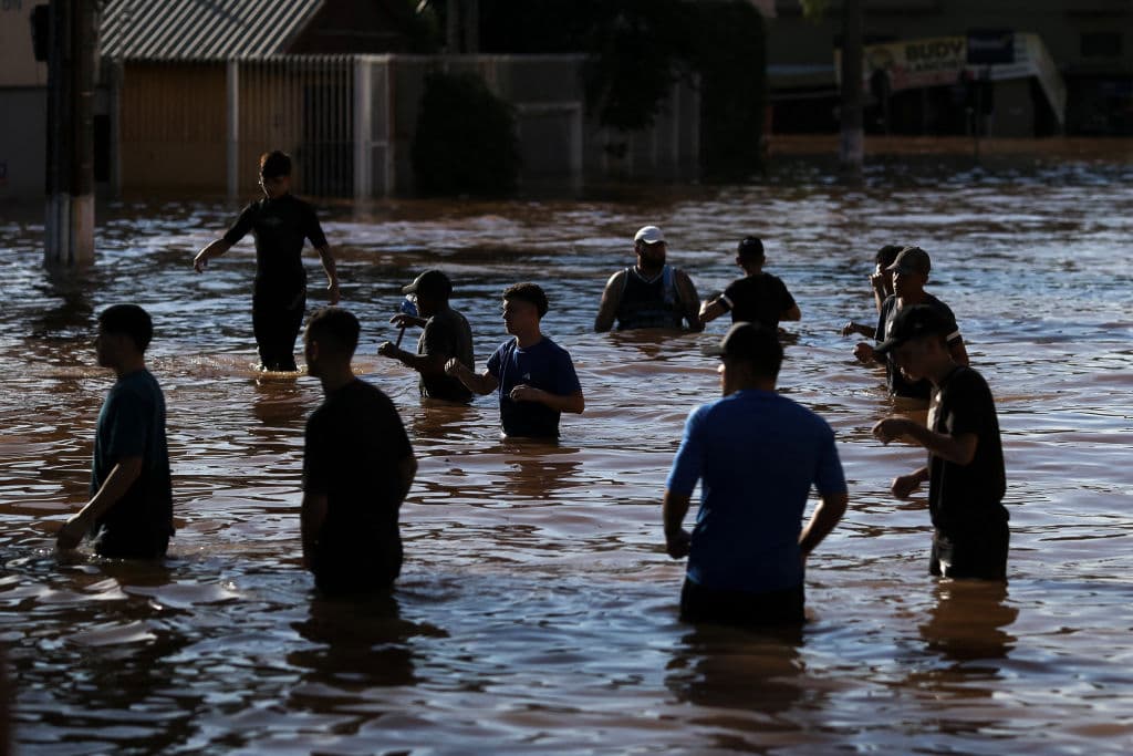 Voluntarios forman un corredor humano para recibir embarcaciones con personas rescatadas de zonas inundadas en el barrio de Sao Joao en Porto Alegre, estado de Rio Grande do Sul, Brasil, el 7 de mayo de 2024. Desde que comenzó el diluvio sin precedentes de la semana pasada, al menos 85 personas han muerto y más de 150.000 fueron expulsadas de sus hogares por las inundaciones y deslizamientos de tierra en el estado de Rio Grande do Sul, según las autoridades.