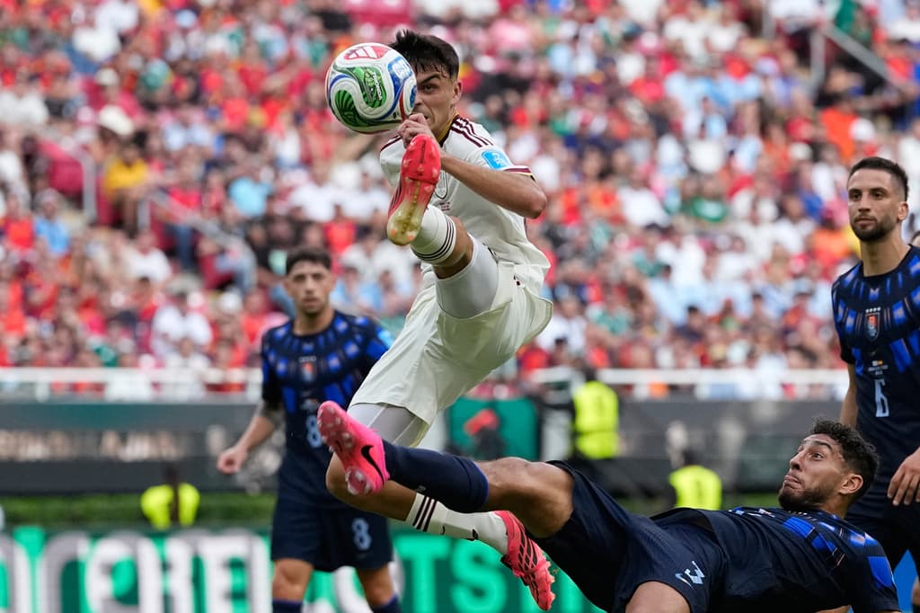 Pedri de España salta fuerte para ganarle el balón a Sebastián Cáceres en una peligrosa jugada cerca del área charrúa.