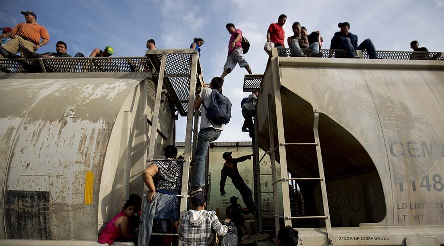 Central American migrants climb on a train during their journey toward the US-Mexico border, in Ixtepec.
