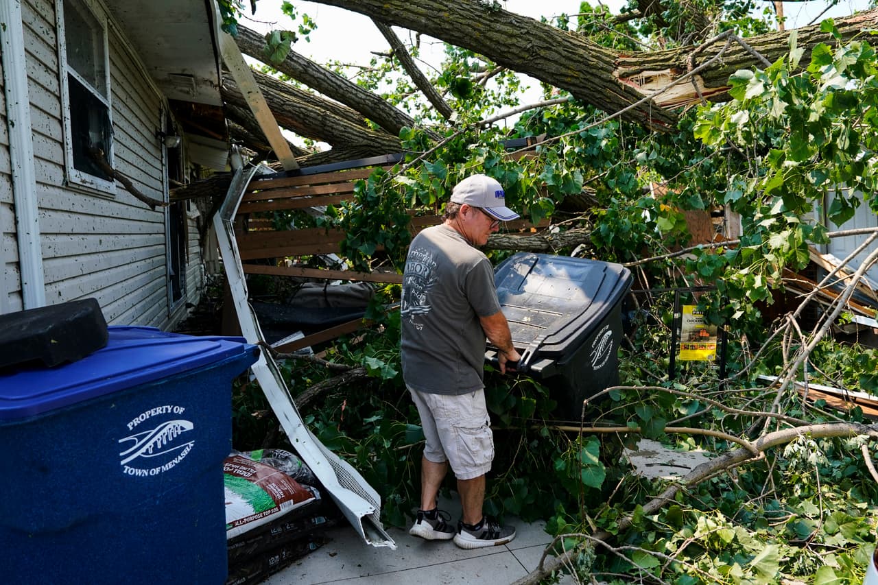 Un hombre ayuda a retirar escombros del patio trasero de una casa dañada tras el paso de un tornado el día anterior, el martes 28 de julio de 2026, en Appleton, Wisconsin.