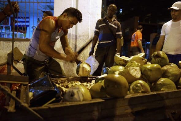 Un vendedor de cocos ofrece la fruta a los cubanos que regresan de trabajar en el barrio de La Habana Vieja.
