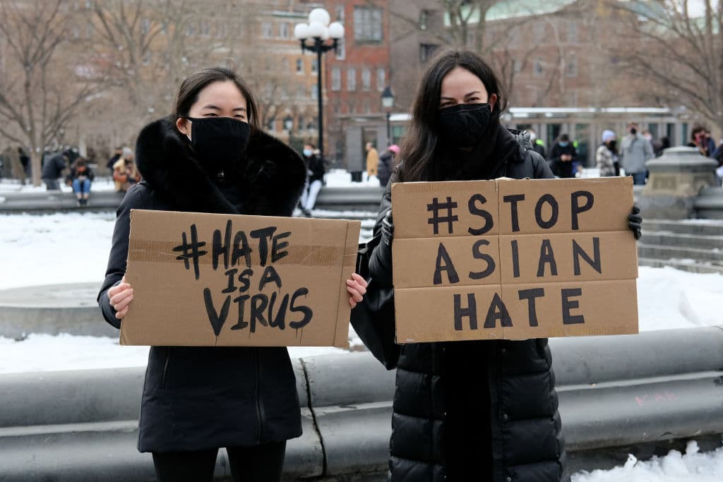 Protestors hold signs that read "hate is a virus" and "stop Asian hate" at the End The Violence Towards Asians rally in Washington Square Park on February 20, 2021 in New York City.