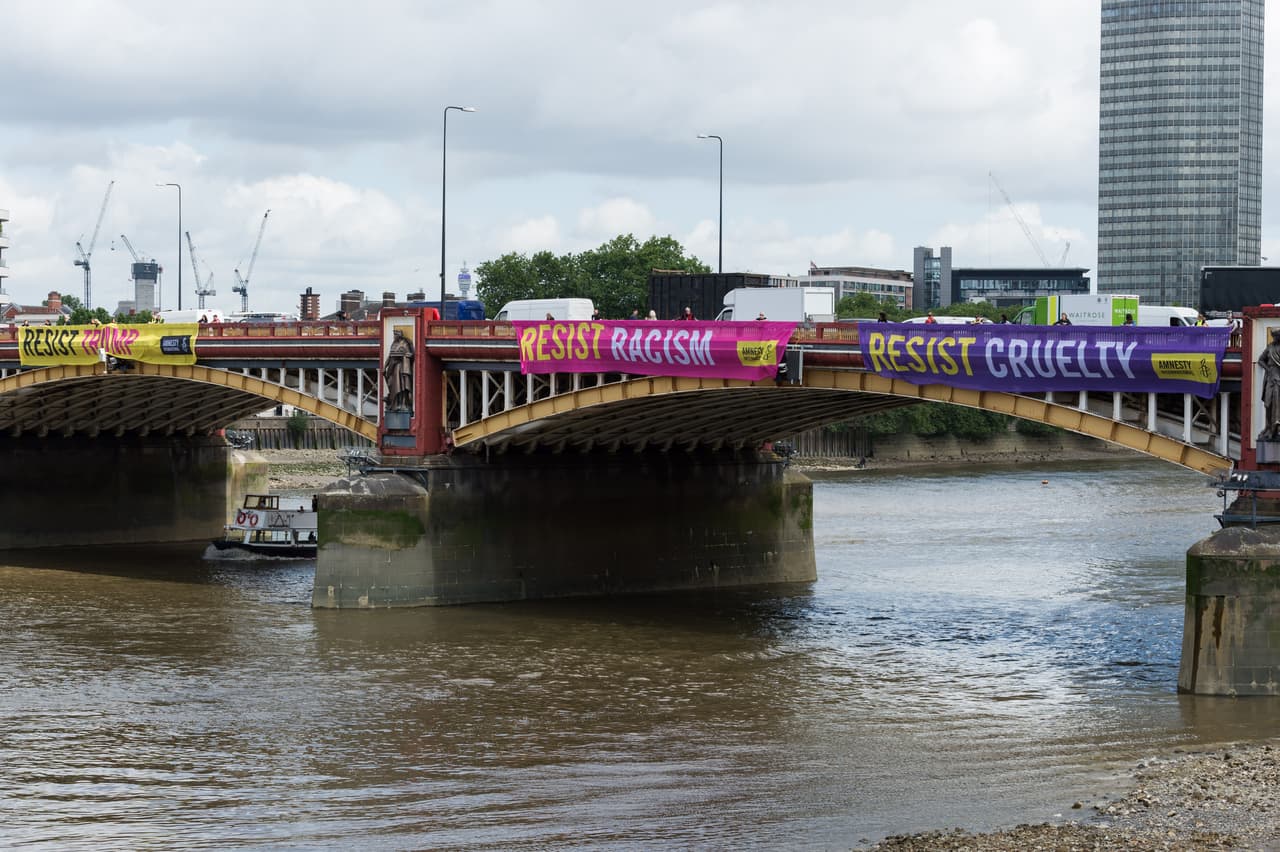 “Resistencia contra Trump”, “resistencia contra el racismo” y “resistencia contra la crueldad”, se lee en los carteles desplegados por activistas de Amnistía Internacional en el puente Vauxhall, frente a la embajada de EEUU en Londres.