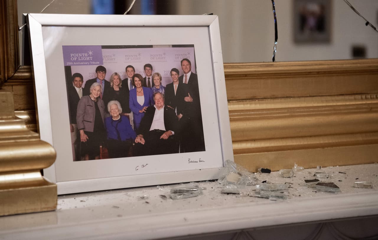 Cristales rotos junto a una fotografía de Nancy Pelosi junto a George H. W. Bush y otros, dentro de la oficina de la representante demócrata.