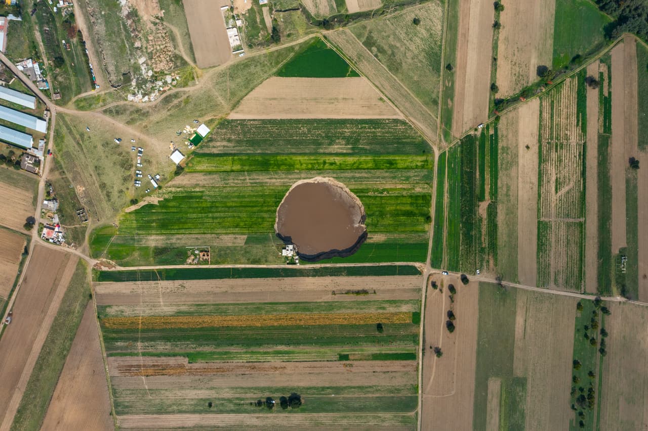 Una vista aérea del
<a href="https://www.univision.com/noticias/de-15-a-300-pies-el-enorme-socavon-que-aparecio-en-mexico-crece-arrasando-lo-que-encuentra-a-su-alrededor-video">socavón</a> que apareció en la comunidad de Santa María Zacatepec, en Puebla,
<a href="https://www.univision.com/temas/mexico-city">México</a>. El hoyo es ya más grande que una cancha de fútbol y las autoridades aseguran que seguirá creciendo.
<br>