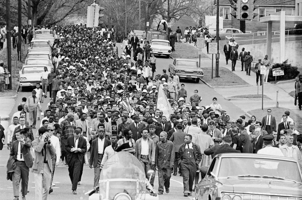 Manifestantes caminan hacia el juzgado detrás del reverendo Martin Luther King Jr. en Montgomery, Alabama, el 17 de marzo de 1965, para protestar por el trato dado por la policía a los manifestantes durante un intento de marcha.