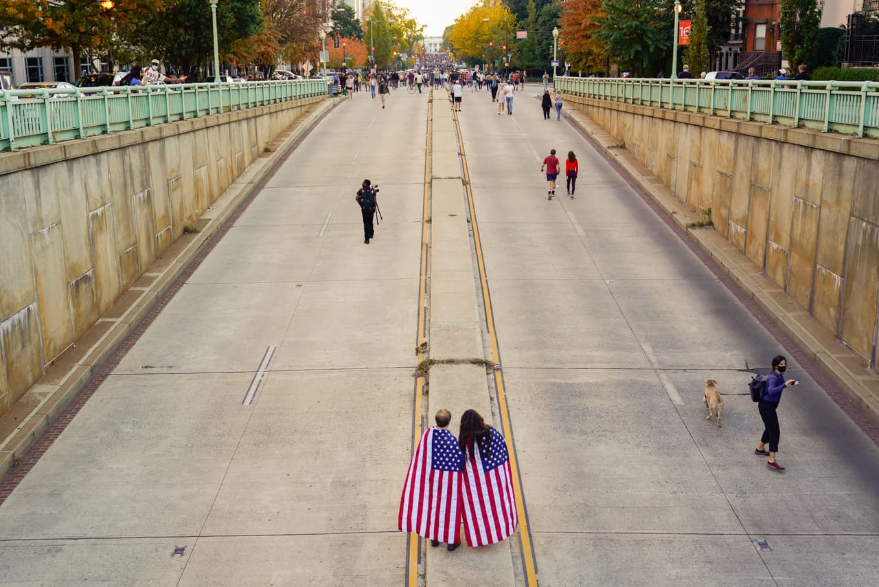 Una pareja con banderas en sus espaldas de camino a la celebración frente a la Casa Blanca.