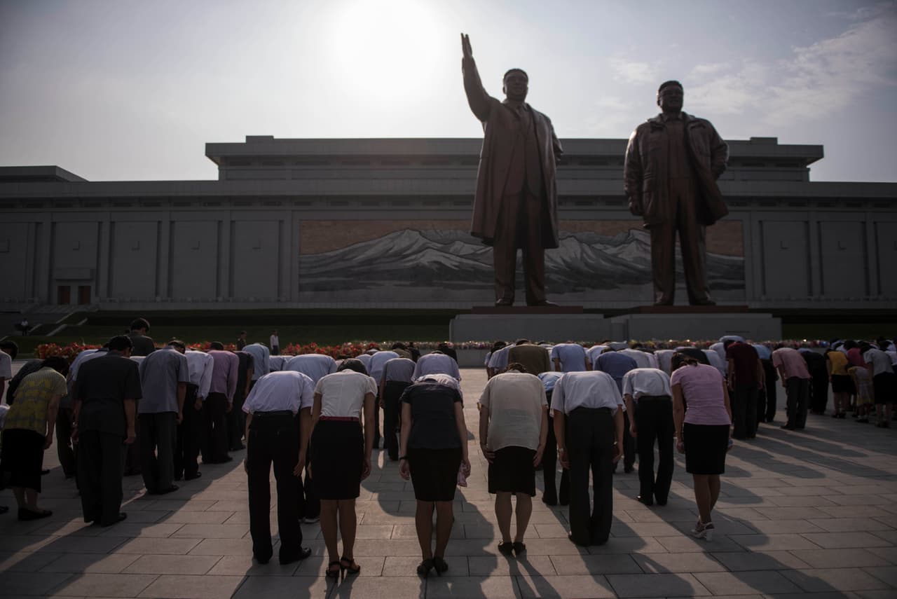 Un grupo de visitantes se inclina ante las estatuas de los exlíderes norcoreanos Kim Il-Sung y Kim Jong-Il, en la colina de Mansu, en Pyongyang. 7 de julio de 2016.
