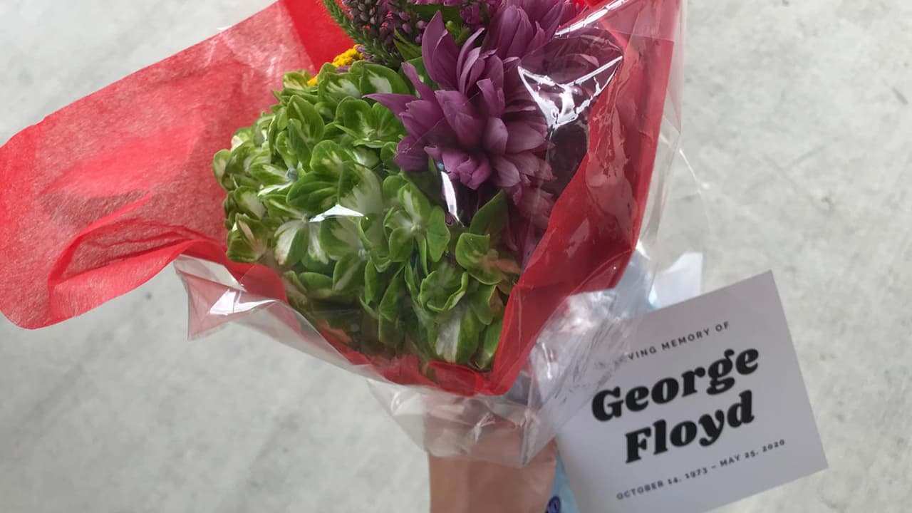 A las personas se les entregan ramos de flores mientras esperan abordar el autobús que los lleva a la iglesia donde se ofrece el servicio de cuerpo presente.