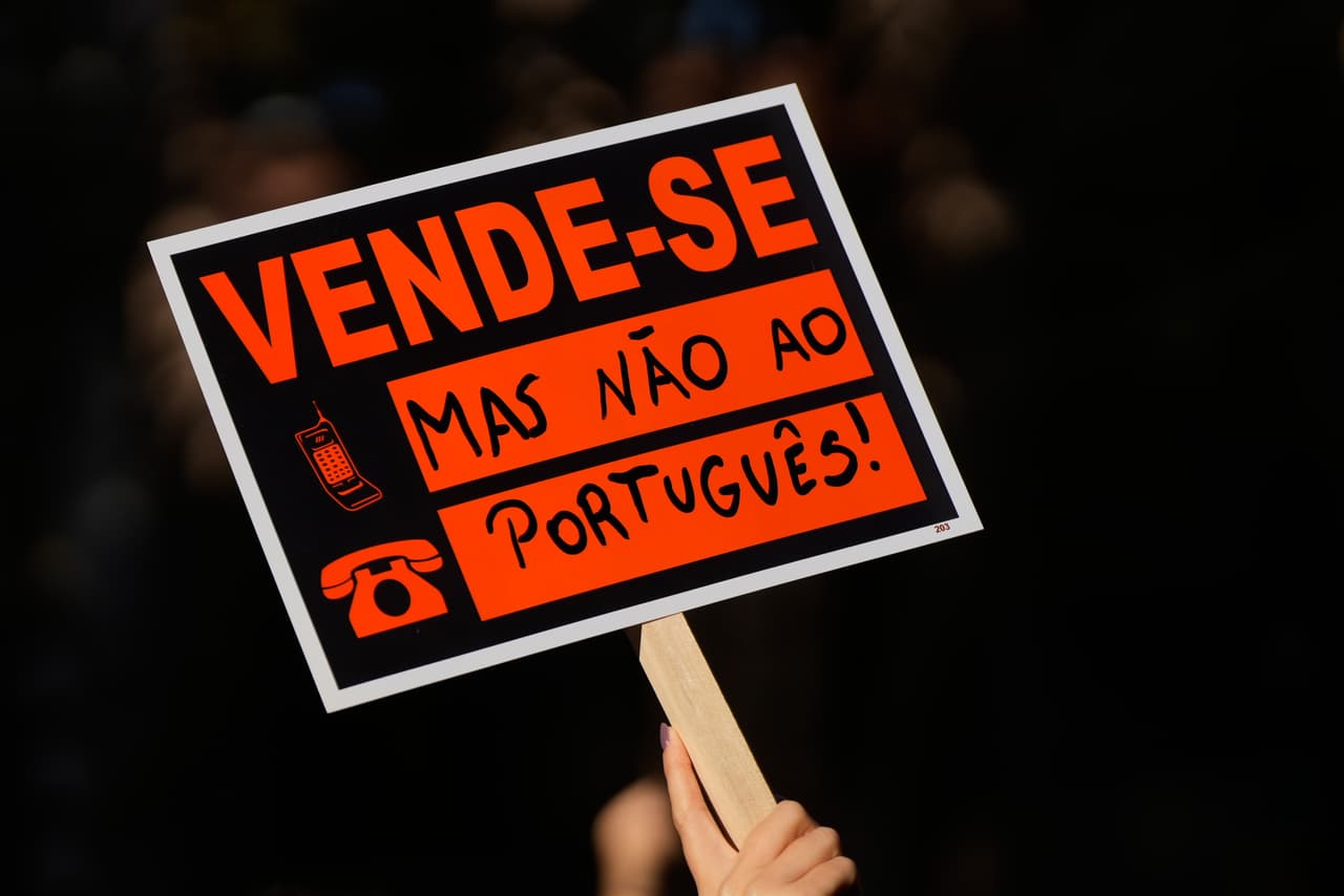 Una persona sostiene una pancarta que dice "¡Se vende, pero no a los portugueses!"