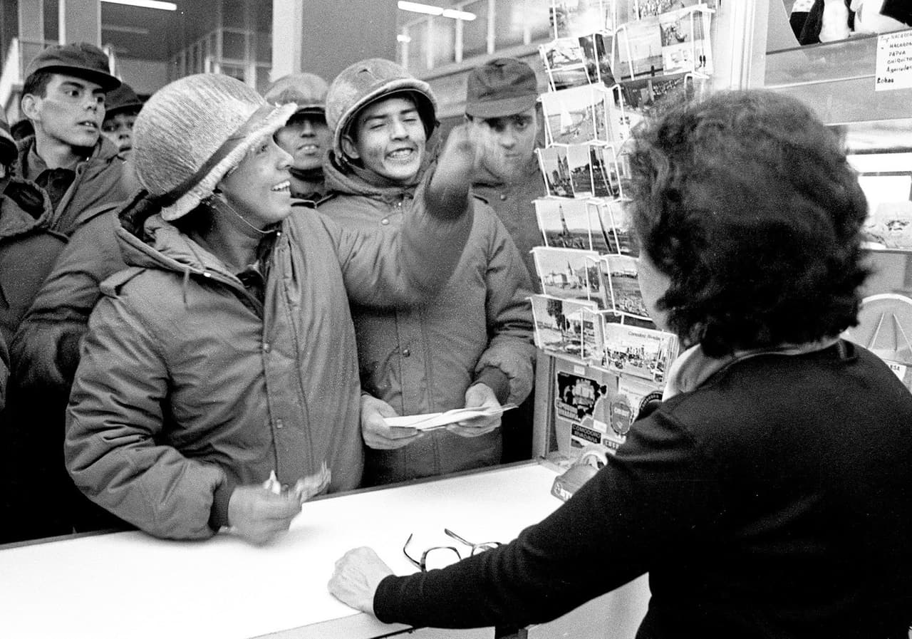 En esta foto del 13 de abril de 1982, un grupo de soldados argentinos compra postales en una tienda de Puerto Argentino (como se rebautizó la capital del archipiélago, Puerto Stanley) Pocos días antes, la primera ministra Margaret Thatcher había anunciado el envío de una fuerza de 11,000 soldados en 8 barcos de guerra y 77 navios auxiliares para recuperar el territorio.
<br>
