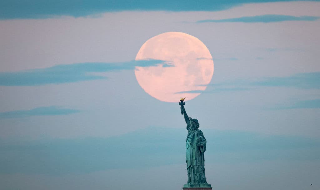 La luna llena de mayo, conocida como la luna llena de flores y es la última superluna del año, se pone detrás de la Estatua de la Libertad, el 7 de mayo de 2020 en la ciudad de Nueva York.