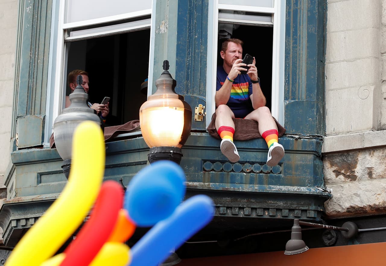 Estas personas observan y apoyan desde la ventana de su casa a la manifestación de la comunidad LGBTQ en Chicago.