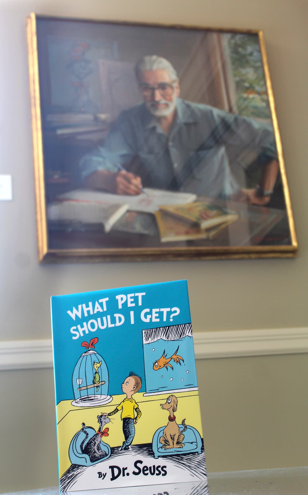 El libro "Qué mascota debería tener?", del Dr. Seuss, se muestra delante de un retrato del autor. Dr. Seuss, cuyo verdadero nombre era Theodor Geisel, escribió e ilustró más de 40 libros antes de su muerte en 1991. Su esposa encontró este texto y las ilustraciones poco después de su fallecimiento, pero el material fue apartado y se redescubrió en 2013.