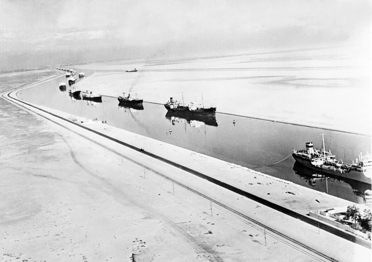 La empresa que administró su construcción, 
<i>Suez Canal Company</i>, se estableció en París, y Egipto dió a esta compañía el derecho a operar el canal durante 99 años después de la finalización de la obra. Su capital era mayoritariamente francés y el resto egipcio, pero en 1875 las acciones de este país fueron adquiridas por Reino Unido. 
<br>
<br>Esta fotografía muestra una fila de barcos navegando por el canal en 1956, una estrategia que se usaba entonces para optimizar el tránsito de barcos, por turnos en una sola vía.
<br>