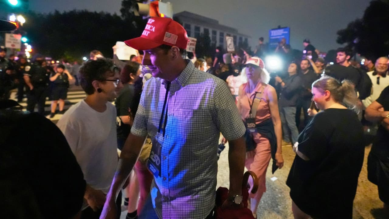 Seguidores del presidente Donald Trump se retiran del desfile militar por el 250 aniversario del Ejército mientras caminan entre manifestantes que protestaban ese mismo sábado 14 de junio de 2025 en Washington.