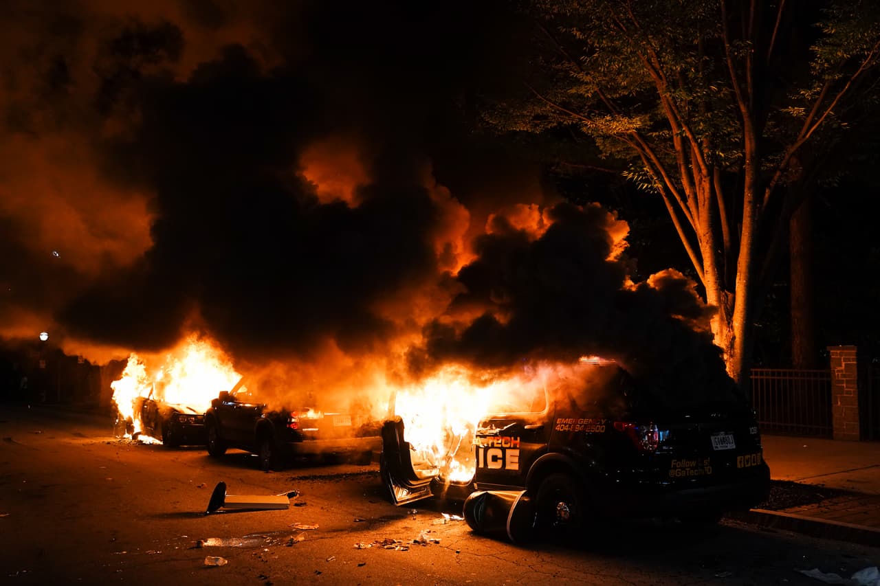 Varios carros resultaron destruídos, incluido una patrulla de la policía, arden durante una protesta el 29 de mayo de 2020 en Atlanta, Georgia.