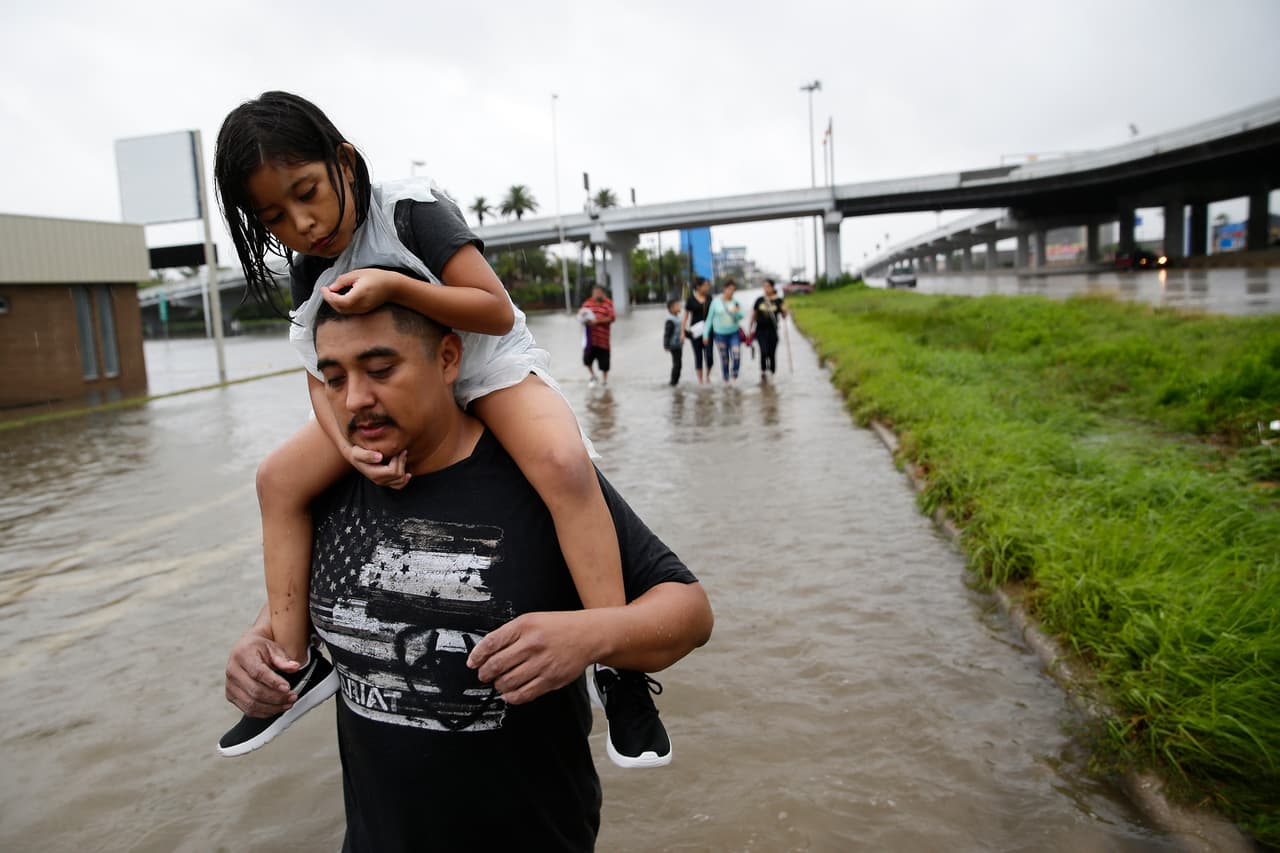 Jesús Núñez huye con su hija Génesis de su hogar inundado en Houston. Harvey, degradado ya a tormenta tropical, sigue generando intensas precipitaciones.