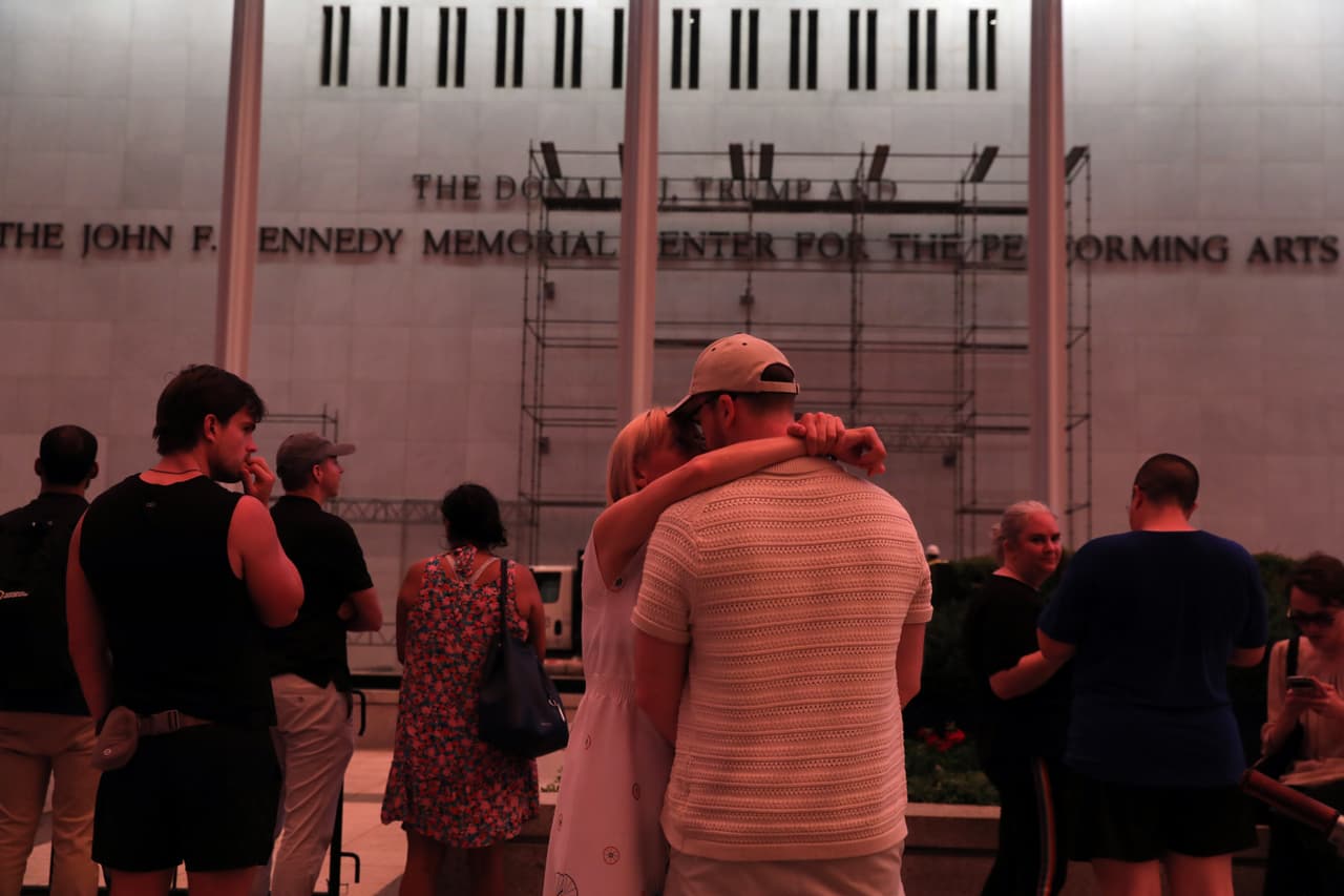 Una pareja se besa frente al Centro John F. Kennedy.