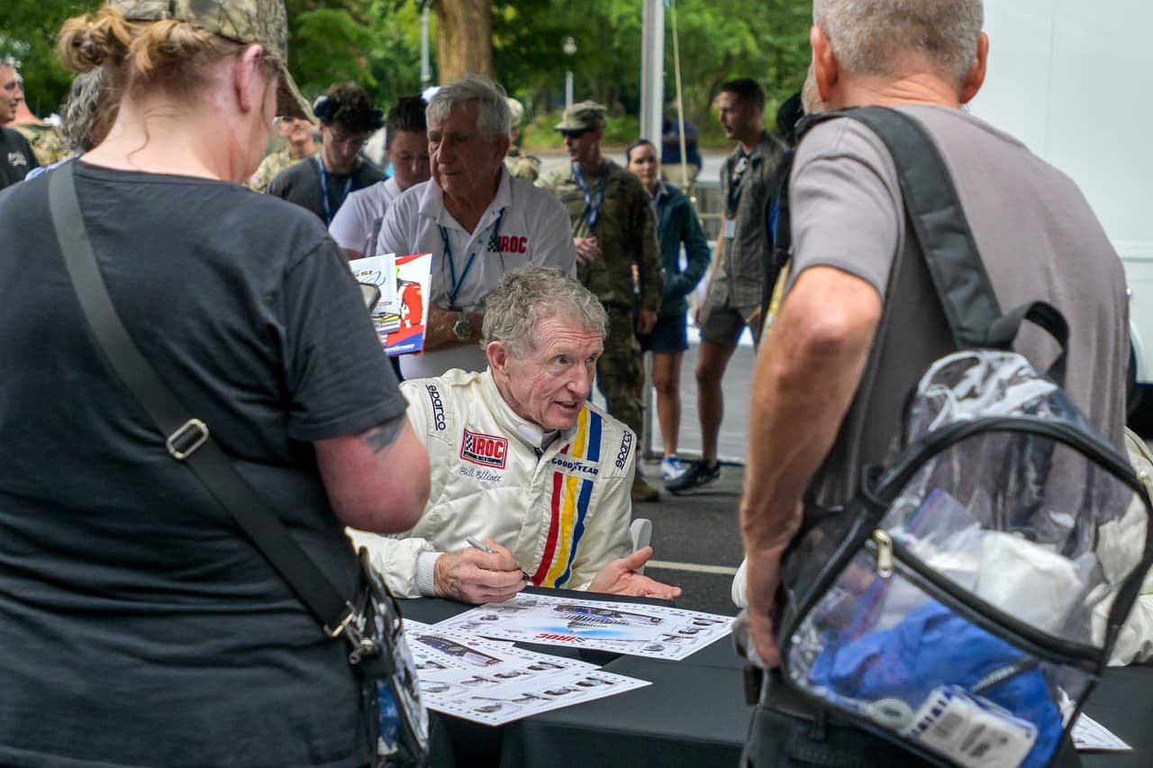 Bill Elliott, en el centro, conversa con su compañero piloto Tommy Kendall mientras firman autógrafos antes del evento de exhibición de la International Race of Champions Racing Series (IROC) en Washington, el sábado 22 de agosto de 2026.