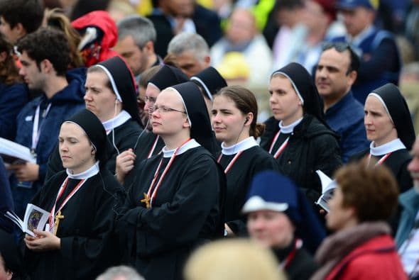 Un grupo de religiosas que asistieron a la ceremonia de canonización escuchan la misa a través de radios y teléfonos celulares con audífonos.