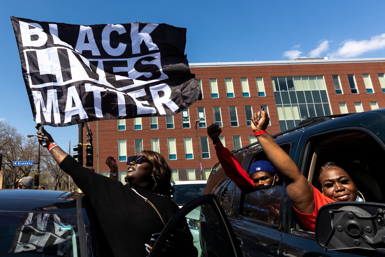 Una mujer agita una bandera que dice "Black Lives Matter" en un lugar cercano al templo Shiloh, donde ocurrió el funeral del joven afroestadounidense Daunte Wright.