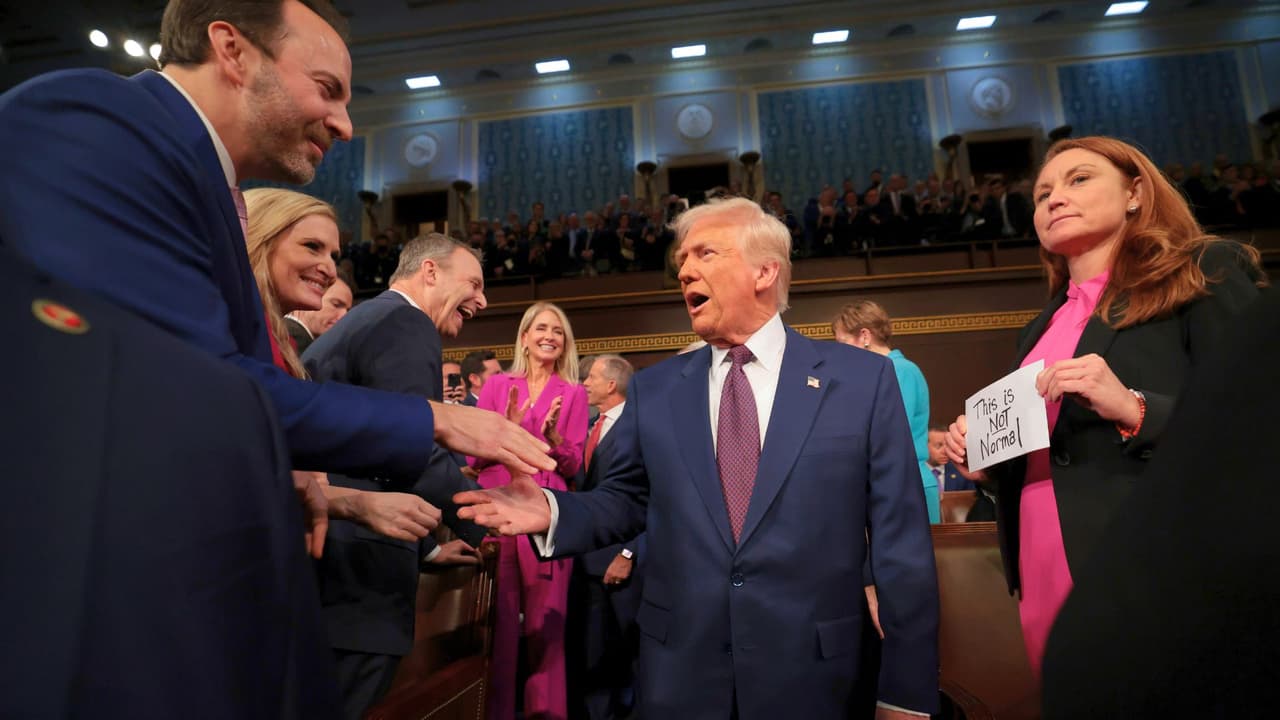 El presidente Donald Trump llega para dirigirse a una sesión conjunta del Congreso mientras la representante Melanie Stansbury, demócrata de Nuevo México, sostiene un cartel que dice: "Esto no es normal".