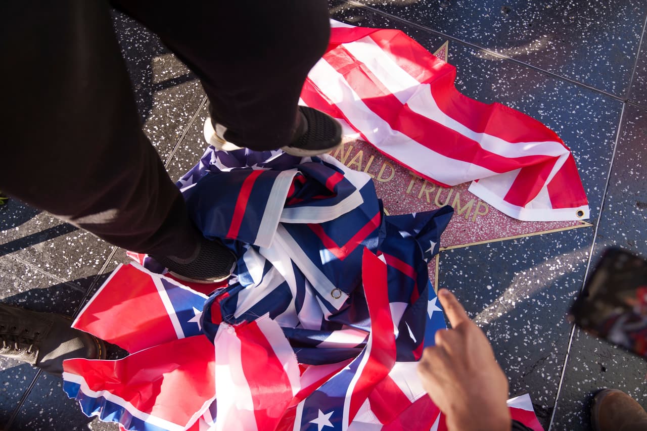 Miembros del "Cuerpo Revcom para la Emancipación de la Humanidad" realizan una protesta visual con un acto simbólico en el que rasgan la bandera estadounidense, la bandera confederada y la bandera de Trump que se encuentran sobre la estrella de Donald Trump en el Paseo de la Fama de Hollywood en Los Ángeles el lunes 20 de enero de 2025.