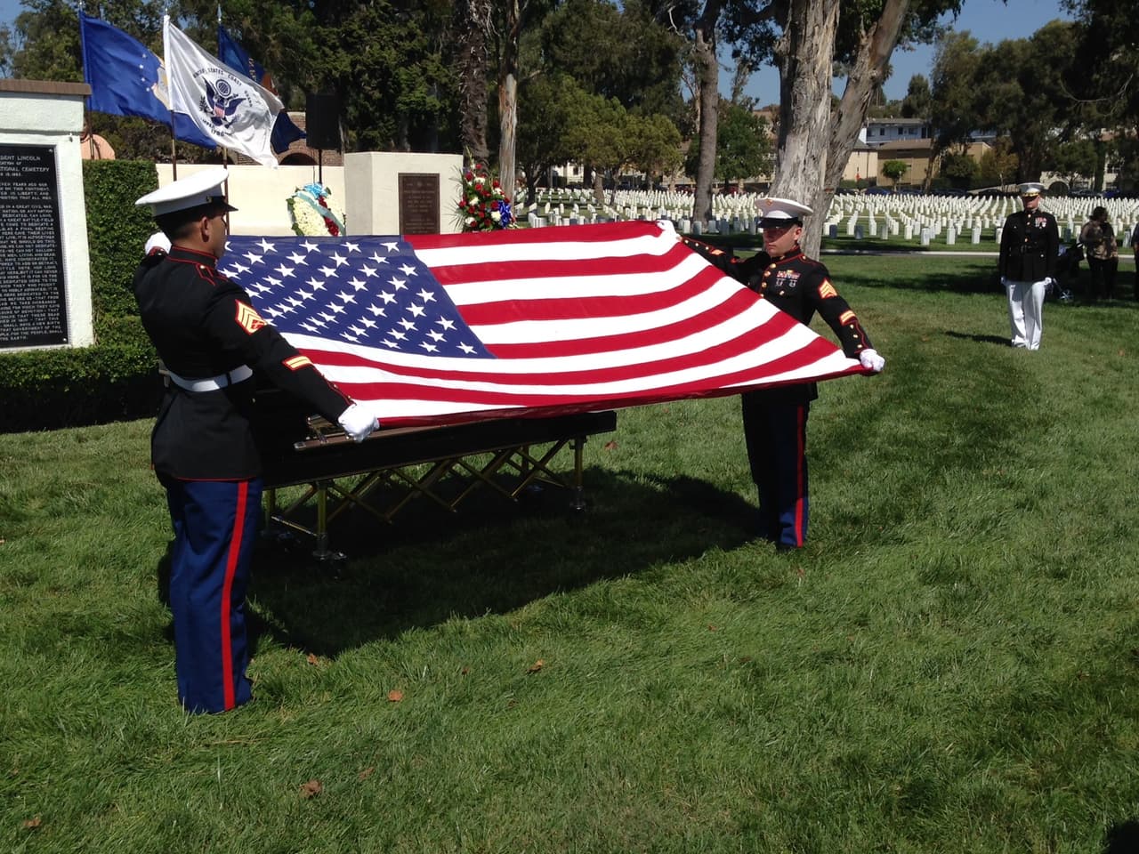 Dos marines pliegan la bandera de Estados Unidos que ha cubierto el féretro.