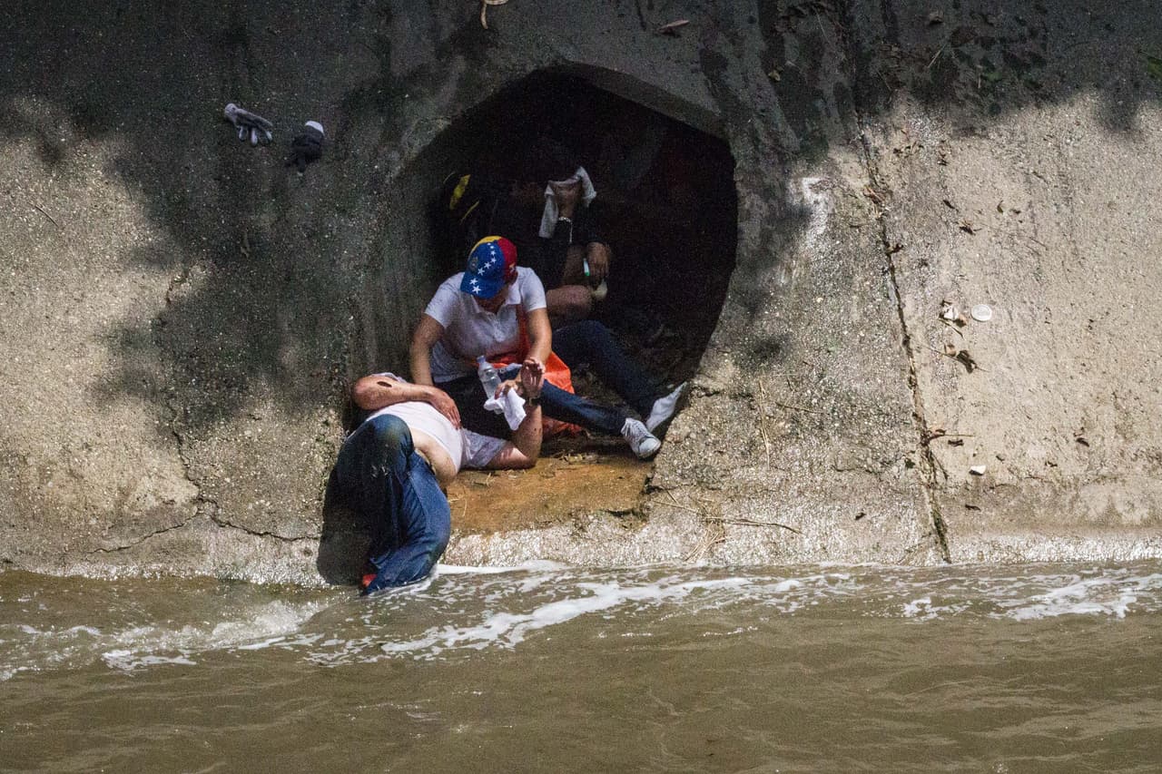 Protesters hide from police at one of the sewage drain that flows into the river.